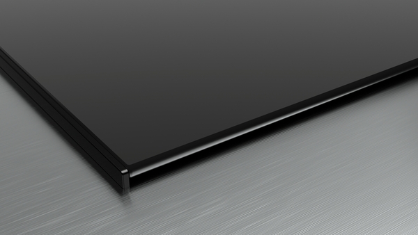 Nahaufnahme einer schwarzen, dünnen Bildschirmkante auf einer silbernen Metalloberfläche.