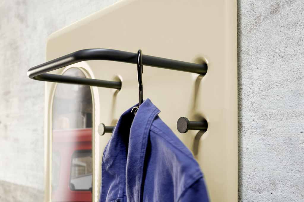 Nahaufnahme einer Wandgarderobe mit schwarzer Kleiderstange und einem blauen Hemd auf einem Kleiderbügel