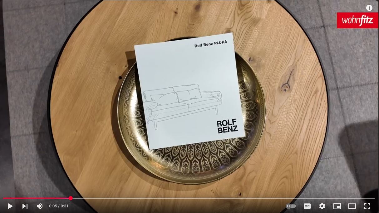 Produktbroschüre von Rolf Benz Plura auf einem Beistelltisch im Möbelhaus