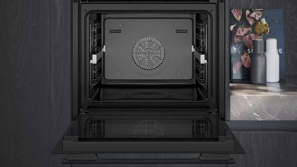 Nahaufnahme des geöffneten Backofens mit Blick auf das vierstufige Einhängegitter und die hochwertige Innenraumbeleuchtung.