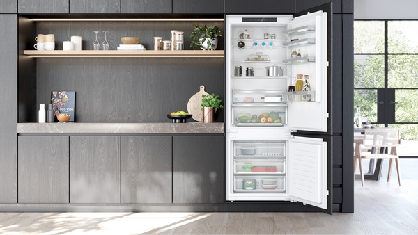 Siemens powerLine Kühl-Gefrierkomination, welche gefüllt ist mit zahlreichen Lebensmittel, verbaut in einer grauen moderenen Küche. 