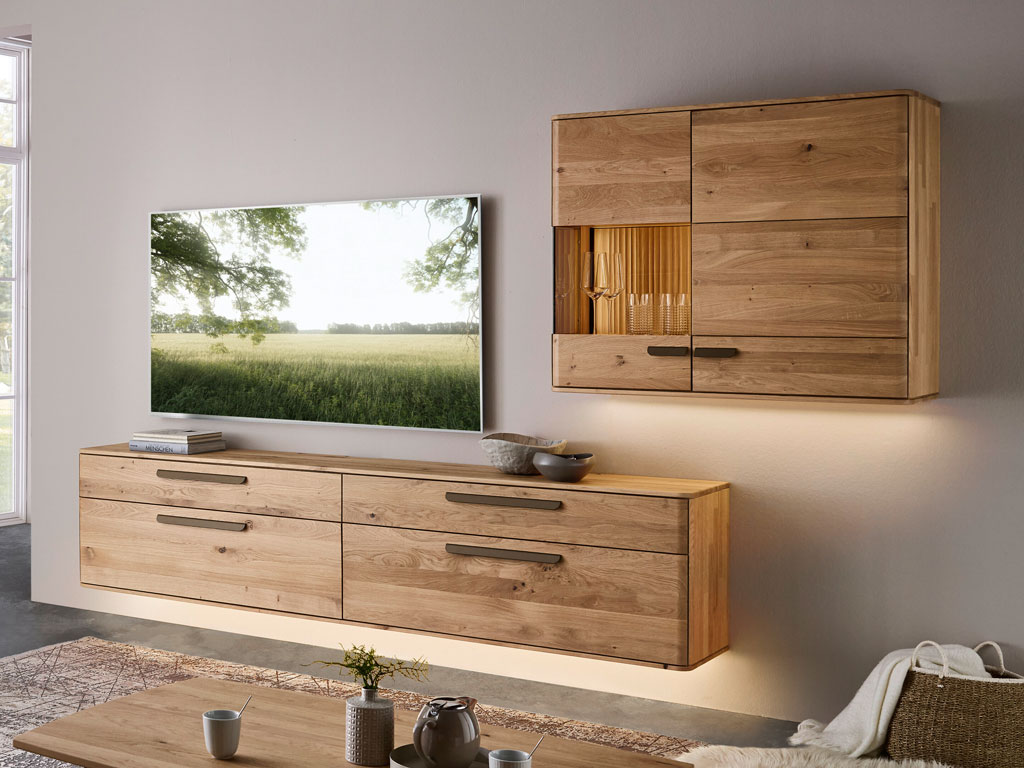 moderne Wohnwand aus Holzt mit großem Hängelowboard und einem Hängeschrank mit Vitrinenausschnitt und Beleuchtung stilvoll dekoriert in einem modernen Zimmer