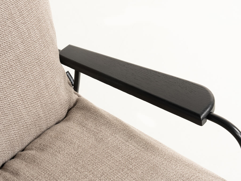 Nahaufnahme eines Armlehnstuhls mit schwarzer Armlehne und beigem Stoffpolster
