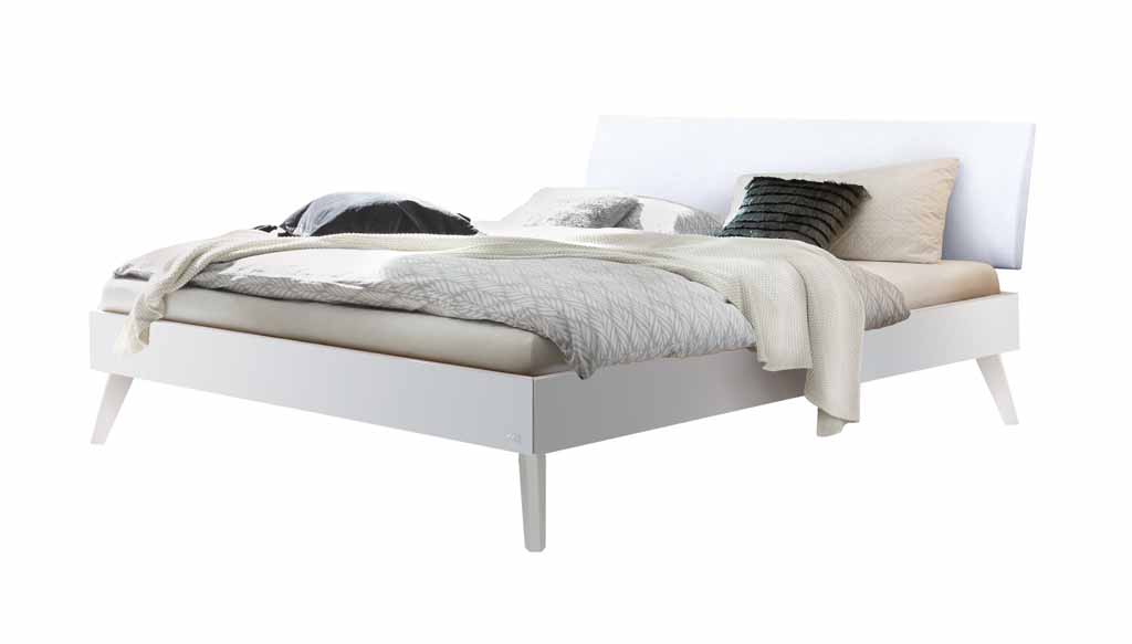 Hasena Trento - Bett Pesaro | Buche weiß, deckend lackiert | Kopfteil Kunstleder weiß Ein stilvolles, weißes Bett mit Bettwäsche in Grautönen und verschiedenen Kissen für ein elegantes Schlafzimmer-Ambiente