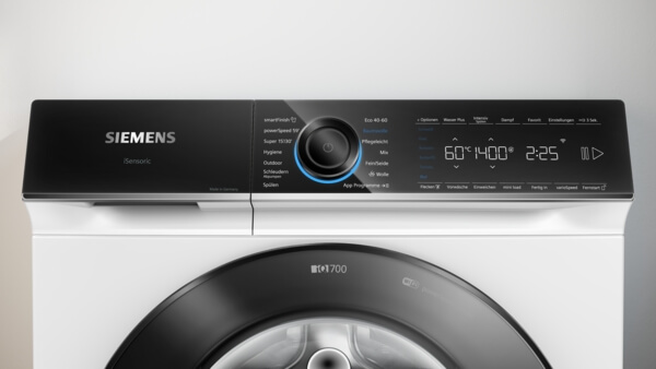Nahaufnahme der schwarzen Bedienblende der Siemens iQ700 Waschmaschine, die das Programmwählrad und das Digitaldisplay mit eingestellter Zeit und Temperatur zeigt.