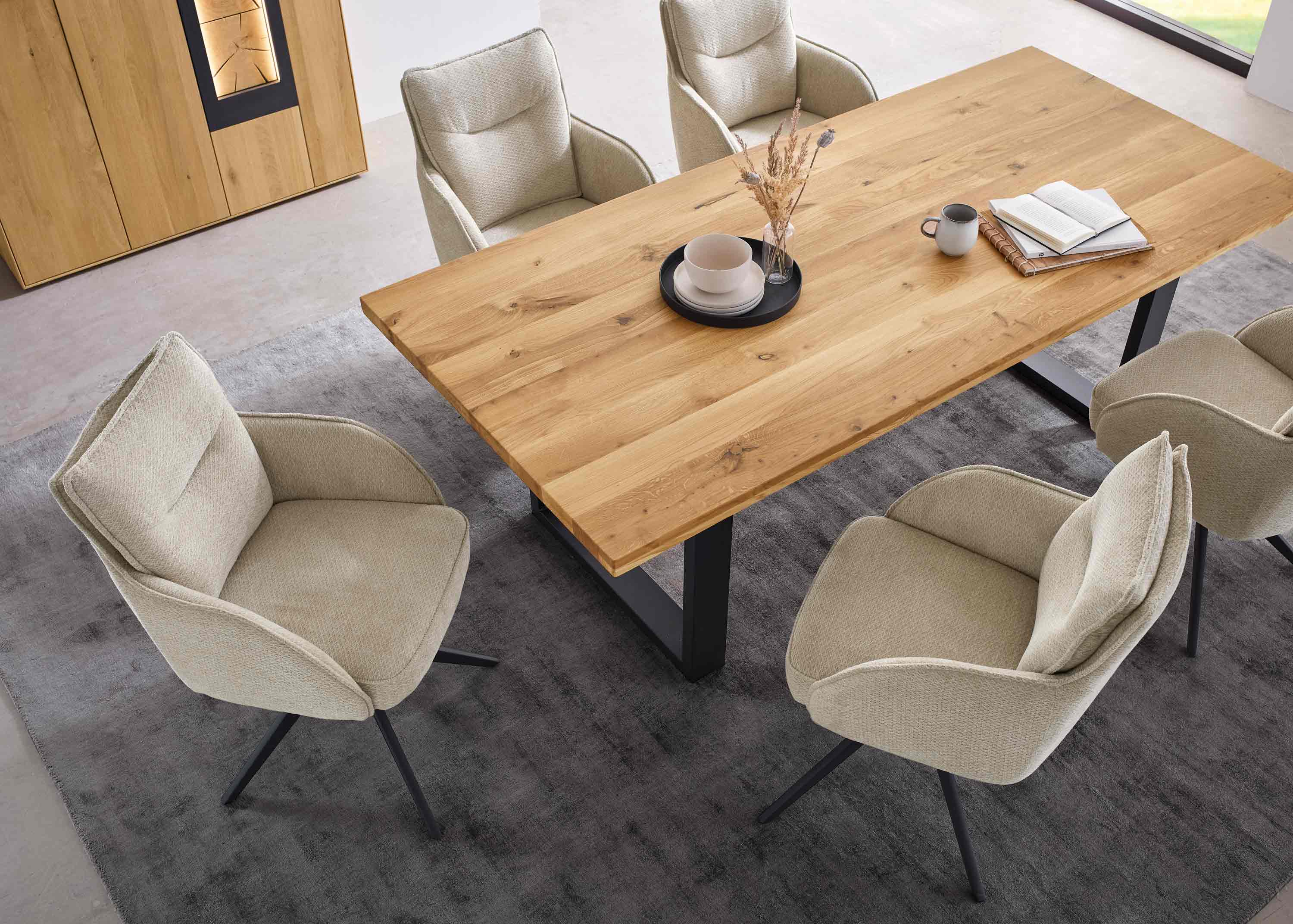 vier beige stühle mit schwarzem gestell an holzesstisch mit metallkufen auf grauem teppich