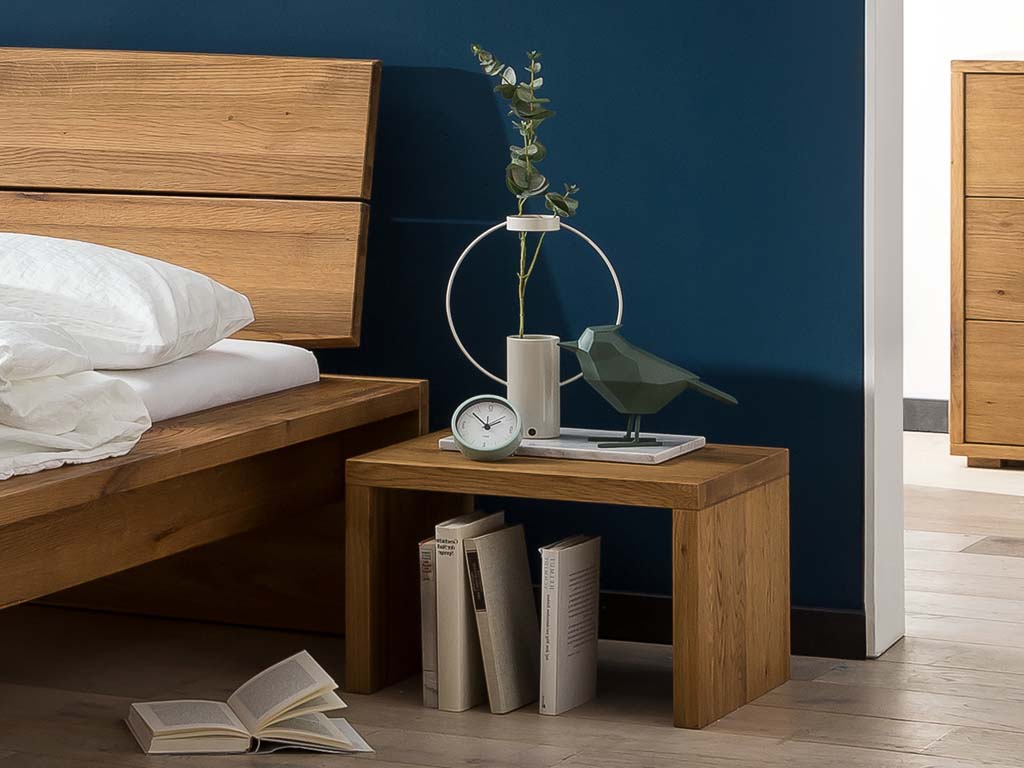 brauner Holznachttisch in rechteckiger einfacher tischform bestehend aus zwei wangen und einer platte stilvoll dekoriert platziert neben einem bett in einem modernen zimmer osta von hasena