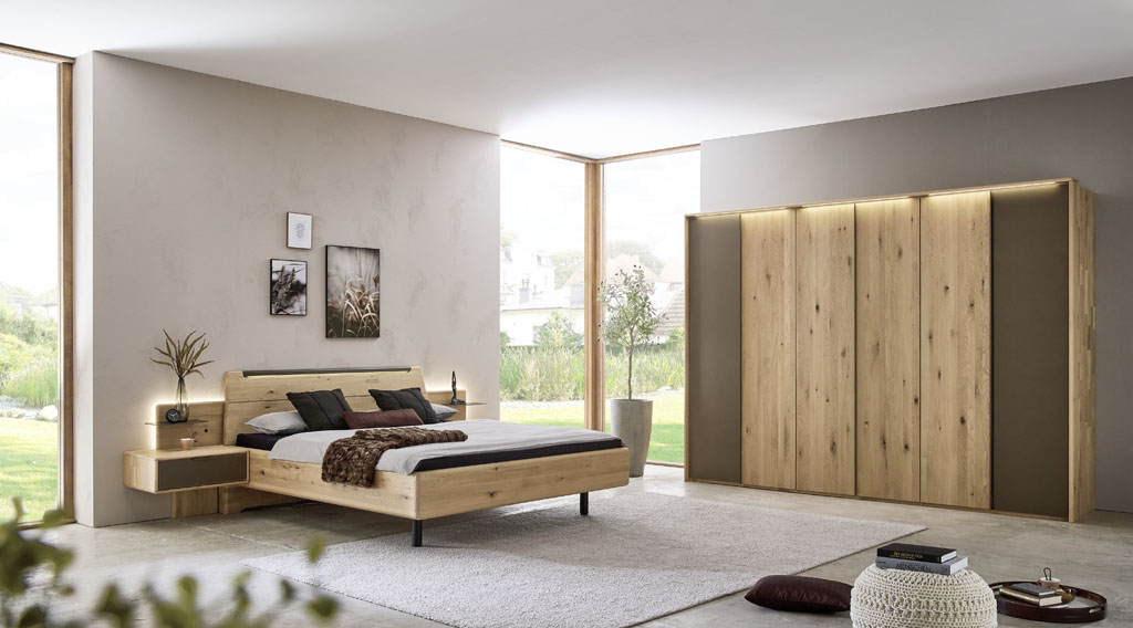 Modernes braunes Schlafzimmer mit einem Schrank mit sechs Türen und einem Bett mit zwei Konsolen stilvoll dekoriert in einem hellen Raum