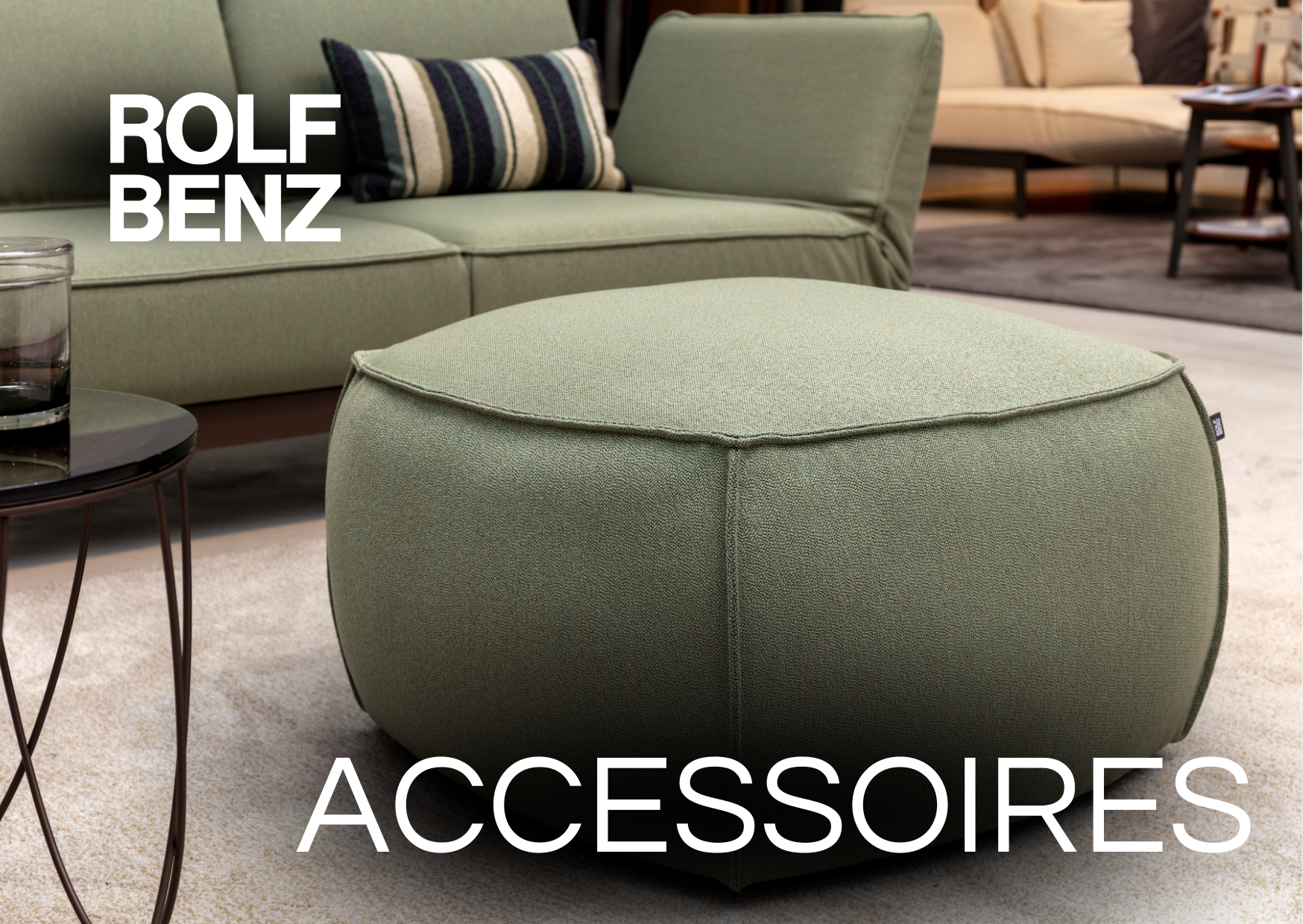 Polsterhocker in grünem Bezug. Bildaufschrift: Rolf Benz Accessoires.