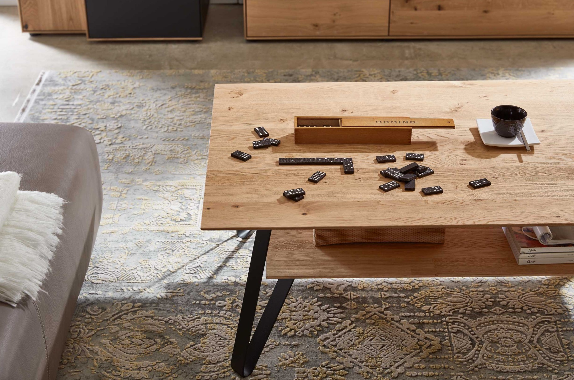 Detailaufnahme eines Holztisches mit schwarzem Gestell mit einem Dominospiel dekoriert
