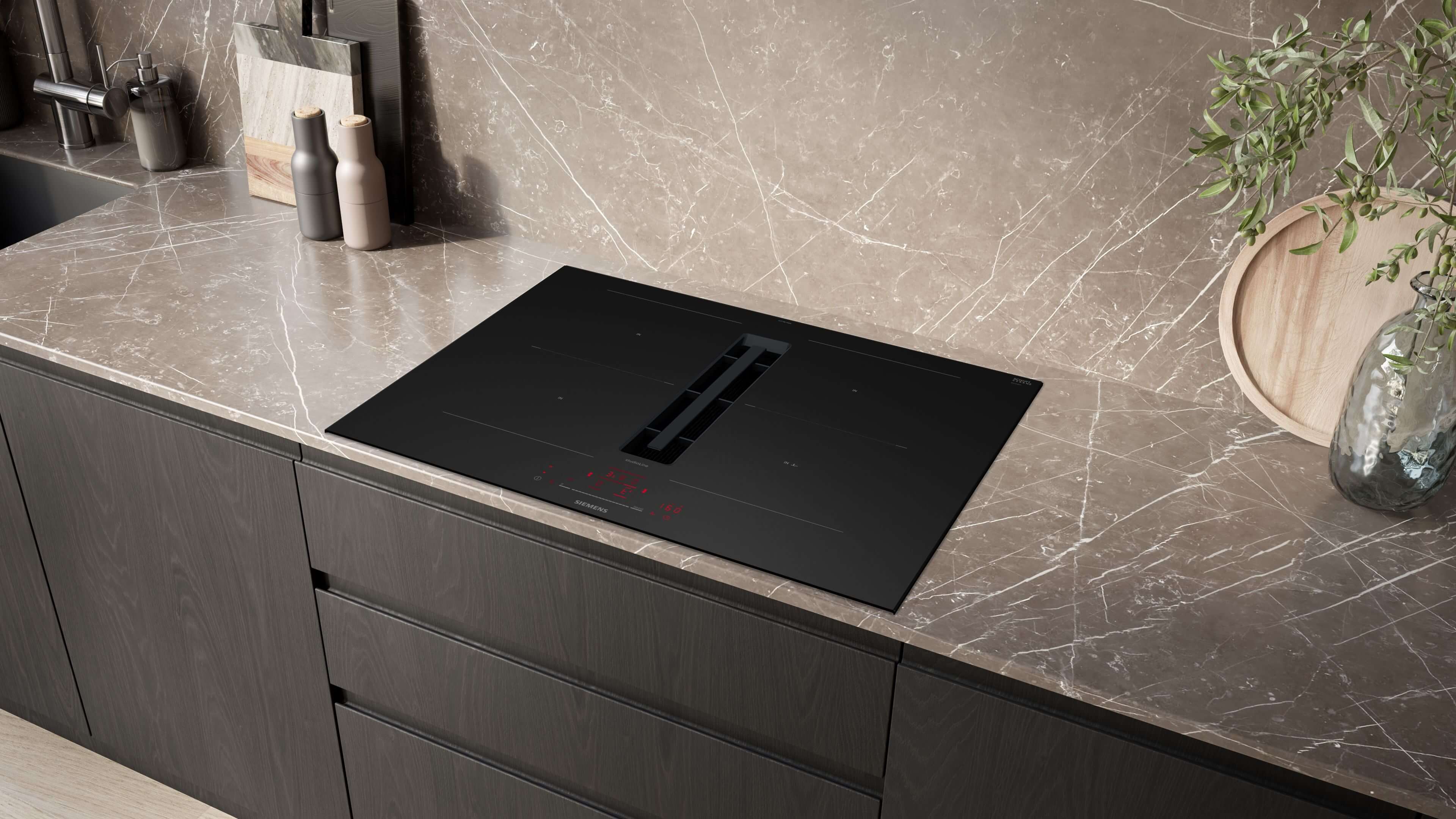 Modernes Siemens studioLine Induktionskochfeld mit integriertem Dunstabzug in eine elegante, dunkle Marmorarbeitsplatte einer Küche eingebaut.