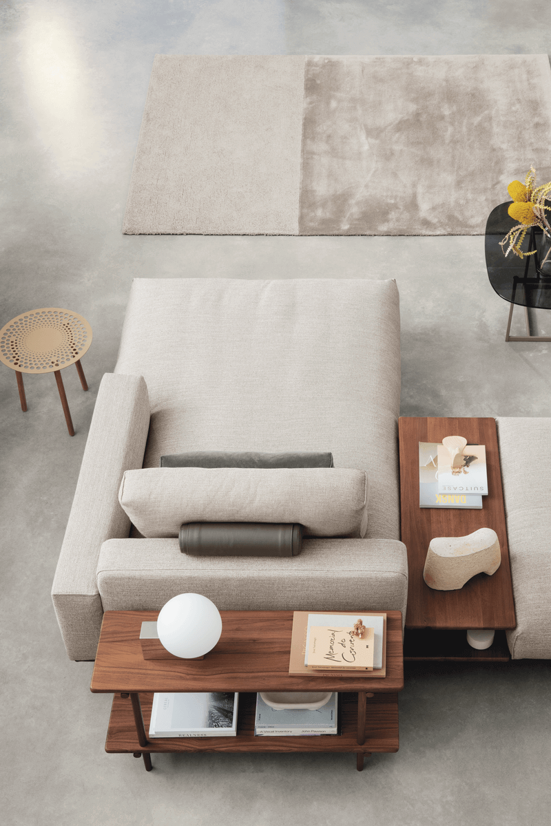 Modernes Wohnzimmer mit beigem Sofa, Holztischen und dekorativem Teppich