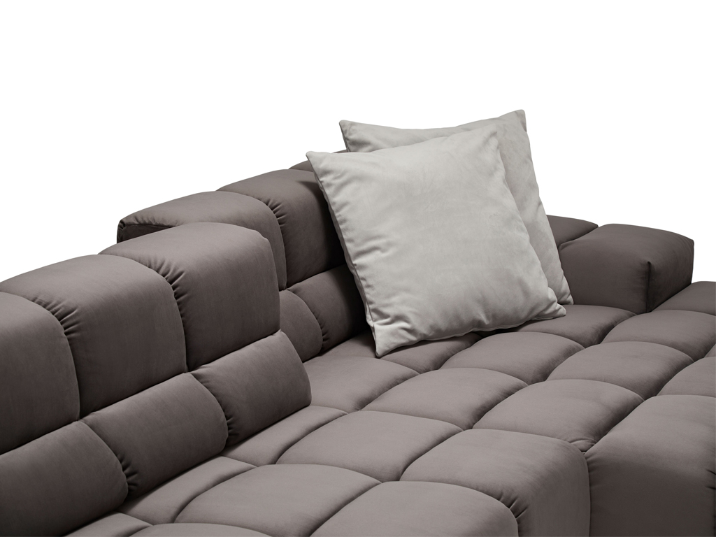 Nahaufnahme eines dunkelgrauen Sofas mit gestepptem Muster. Zwei hellgraue Kissen liegen auf der Rückenlehne.
