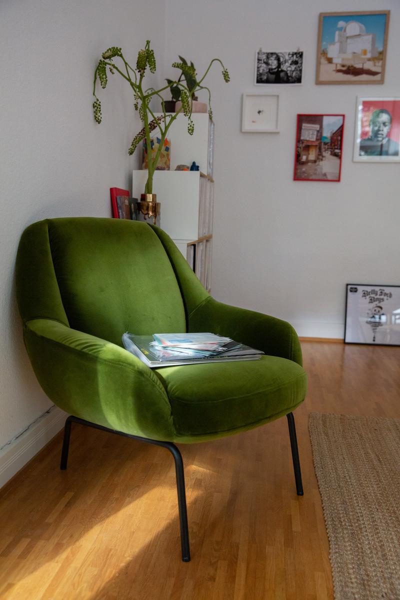 freistil Rolf Benz 138 - Sessel | B: 76 cm Grüner Sessel aus Samt in einem stilvoll dekorierten Wohnzimmer mit Holzboden, Bücherregal und Wandbildern