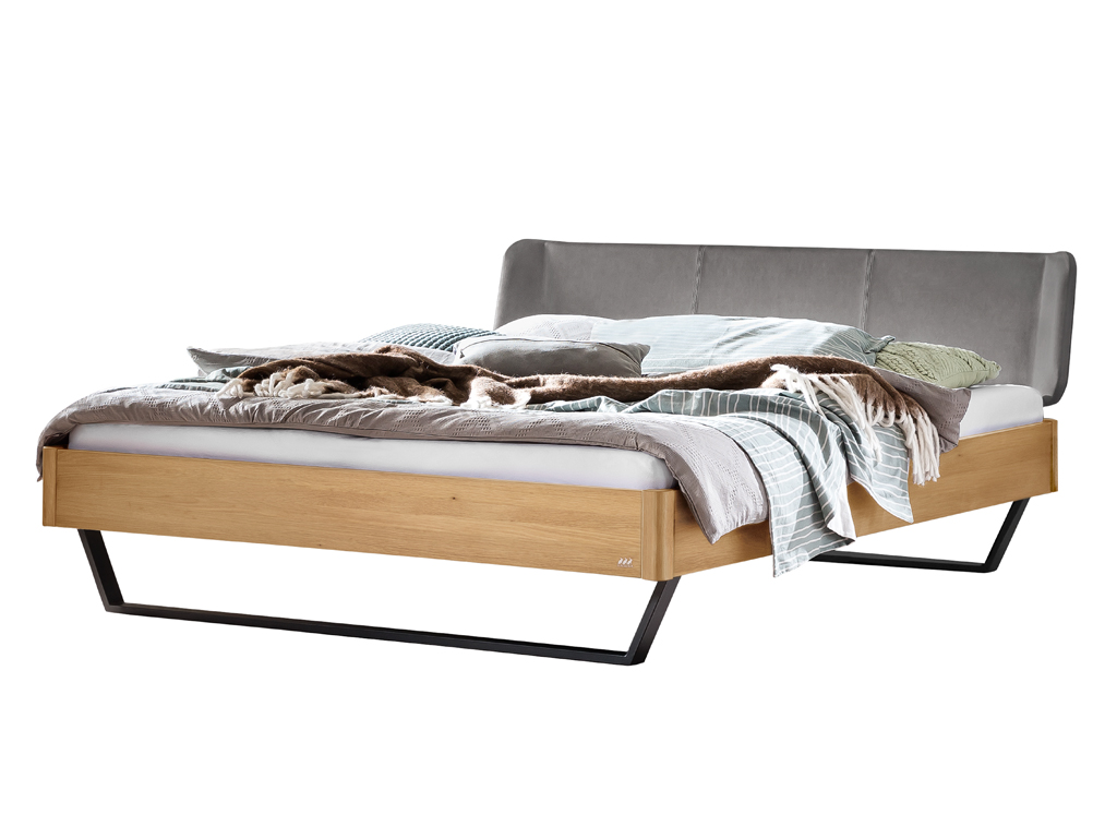 Ein Holzbett mit hellem Eichenrahmen, einem gepolsterten, anthrazitfarbenen Kopfteil und schwarzen Metallfüßen. Die Bettwäsche ist in verschiedenen Grau-, Blau- und Brauntönen dekoriert.