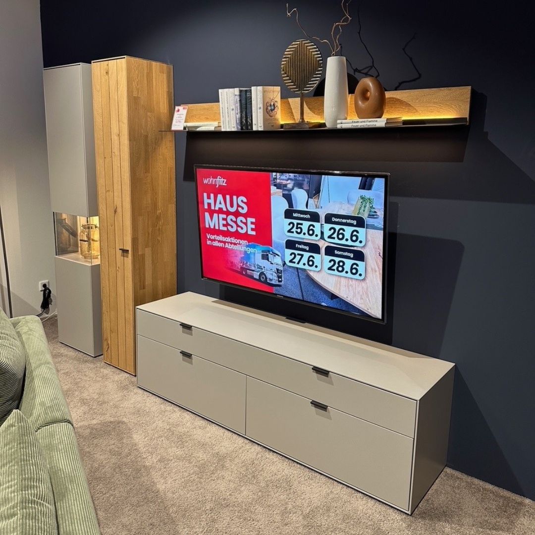 Wohnwand mit Fernseher. Wohnwand in grau mit Lowboard und Hochschränken mit Holzakzenten