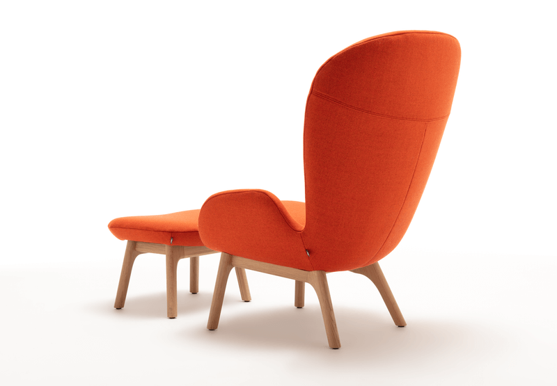 Rückansicht eines modernen Sessels mit passendem Fußhocker, beide in leuchtendem Orange bezogen und mit Holzbeinen ausgestattet.