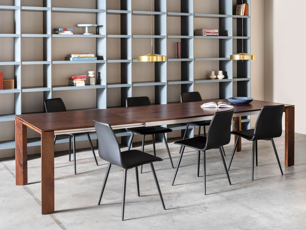 Sudbrock Pondus - Esstisch mit Auszug | B: 180 cm | Kirschbaum brazil massiv Esszimmer mit großem rechteckigen Holztisch, sechs schwarzen Stühlen und einem grauen Regal im Hintergrund