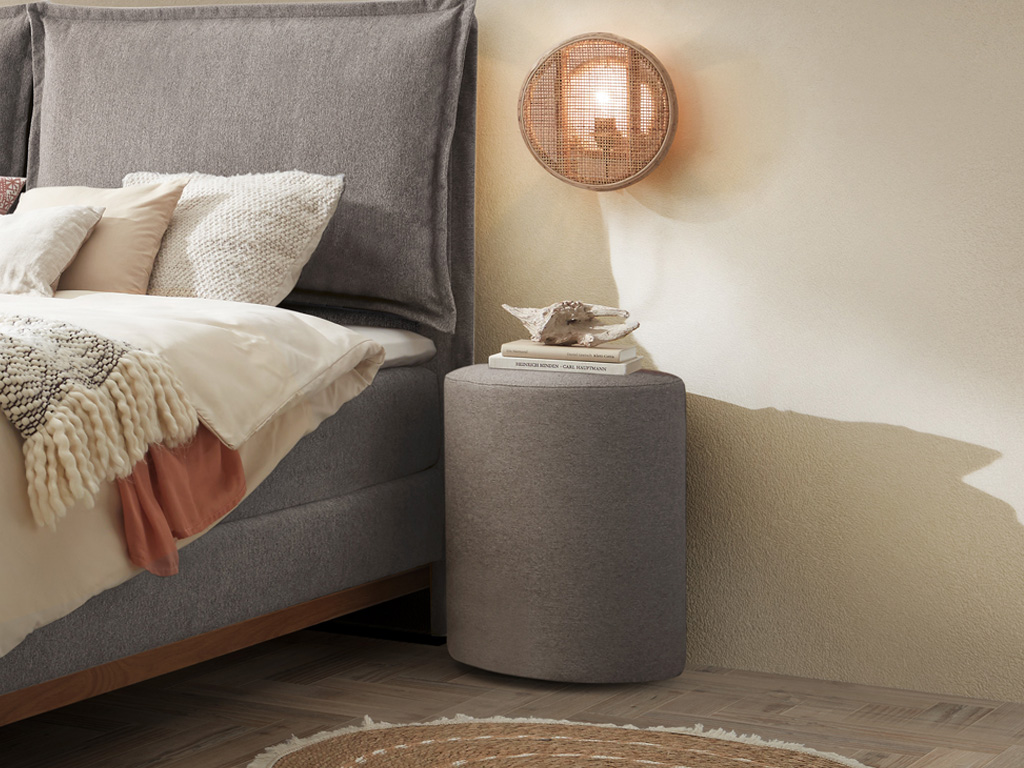 grauer runder hocker vor stilvoll dekoriert an einem bett in einem modernen zimmer Dean von Hasena