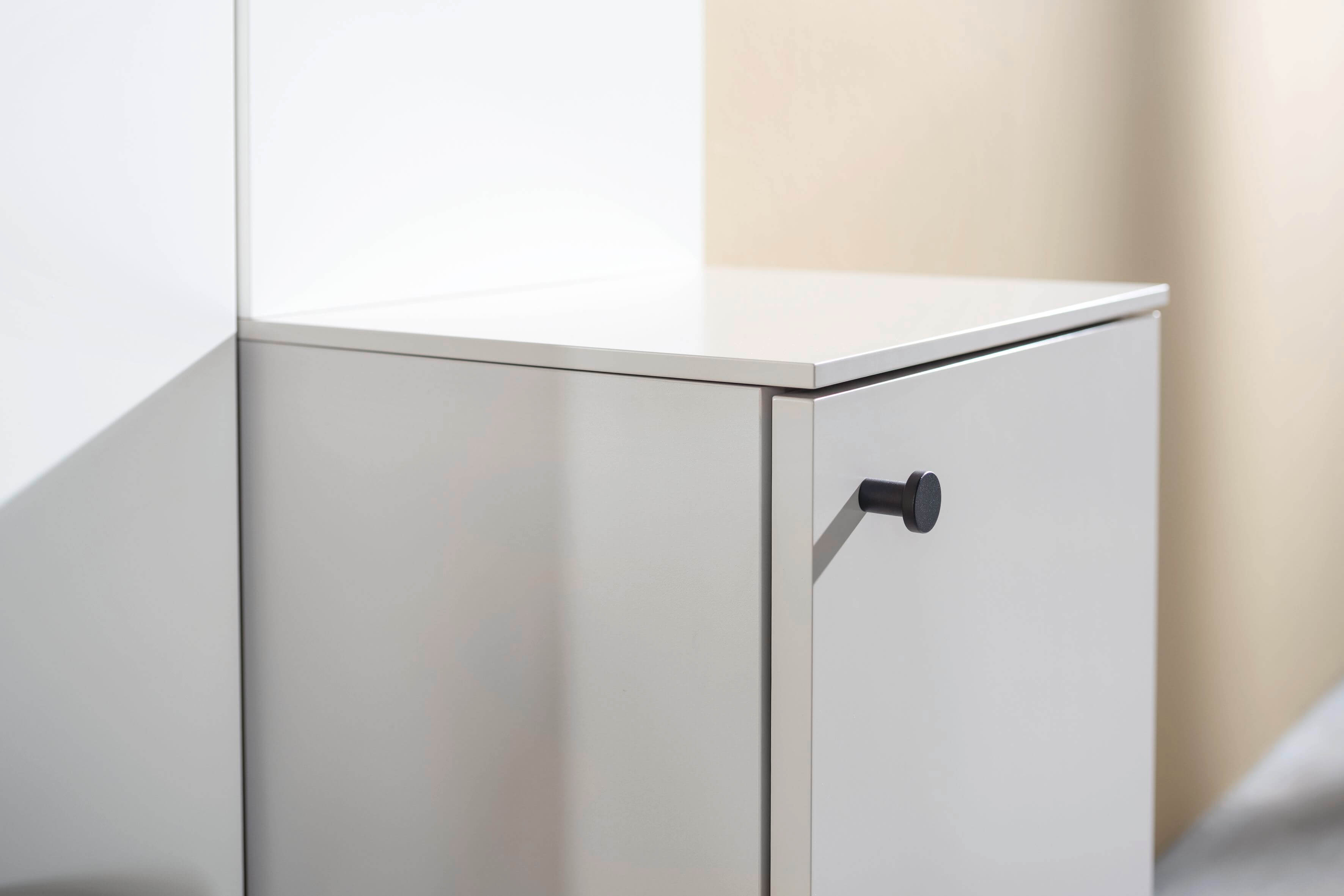 Nahaufnahme eines minimalistischen weißen Schranks mit schwarzem Griff im modernen Design