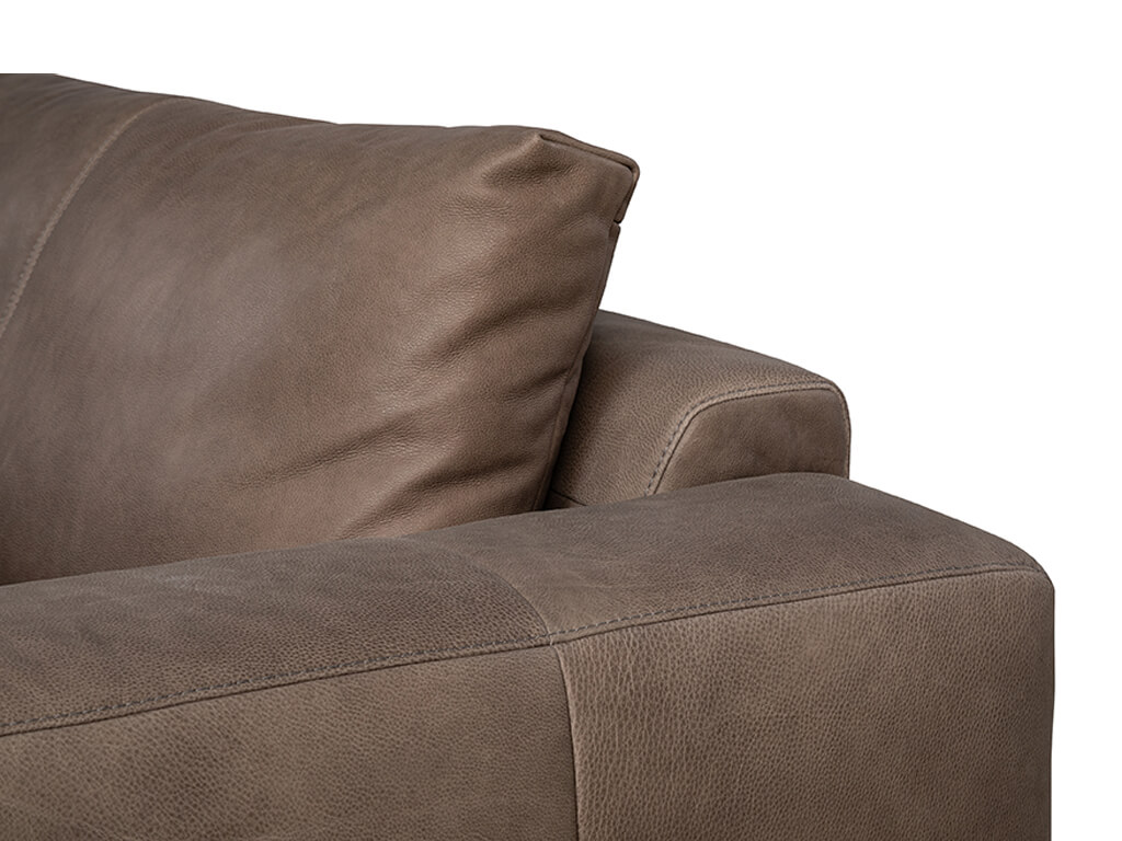 Nahaufnahme eines braunen Ledersofas, die das Rückenkissen, die Armlehne und die Sitzfläche mit sichtbaren Nähten zeigt.