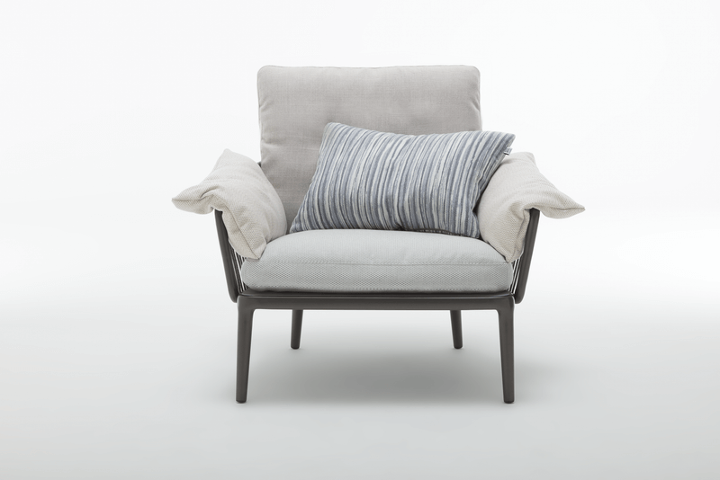 Ein moderner Lounge-Sessel mit einem gestreiften Kissen in neutralen Farben, ideal für Wohnzimmer oder Leseecken.