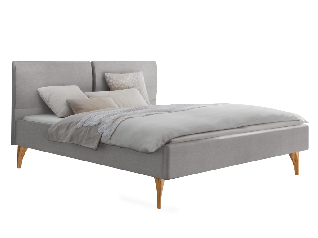 Ein graues, gepolstertes Bett mit einem geteilten Kopfteil und hellen Holzfüßen, bedeckt mit hellem Bettzeug und Kissen.