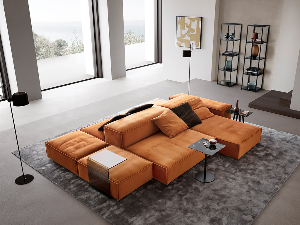 designwerk Puzzle - Wohnlandschaft | B: 340 cm Helles Wohnzimmer mit einem großen, orangefarbenen Sofa, modernen Regalen und dekorativen Elementen, die ein gemütliches und stilvolles Ambiente schaffen.