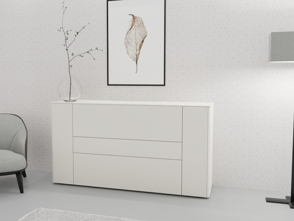Sudbrock Goya - Sideboard | 2 Türen, 2 Schubladen, 1 Klappe | B: 175,2 cm | Lack blütenweiß Weiße Kommode mit Schubladen, dekoriert mit einer Vase auf einer glatten Oberfläche, neben einem grauen Stuhl und einer Stehlampe in einem stilvollen Raum.