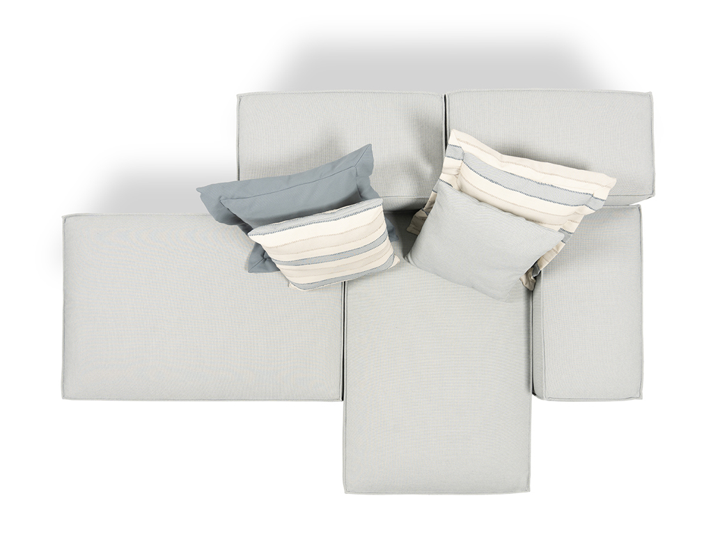 Eine Draufsicht auf ein hellgraues, modulares Outdoor-Sofa, das aus fünf Elementen besteht und eine T-ähnliche Form bildet. Vier Zierkissen in Blau, Hellgrau und gestreift sind auf den Rückenelementen platziert.