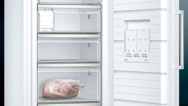 Ein offener Gefrierschrank mit einem verpackten Lebensmittel im unteren Fach des Geräts. Der Innenraum ist sauber und modern gestaltet.