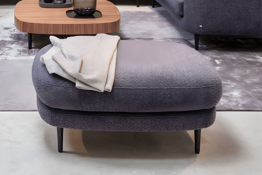 Hocker in Dunkelgrau und Decke in beige darauf