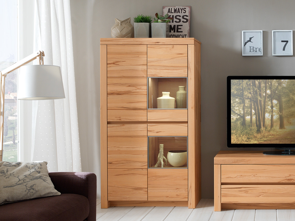 Wöstmann Soleo 3000 - Vitrinenschrank | Type 4903/4904 | B: 93,4 cm | konfigurierbar Ein gemütlich eingerichtetes Wohnzimmer mit einem hellen Holzschrank, Keramikdekoration, einem Sofa und einem Fernseher auf einem Holzschrank.