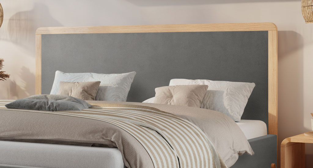 Nahaufnahme des grauen Kopfteils mit massivem Eichenholzrahmen an einem modernen Polsterbett (KI-generiert)