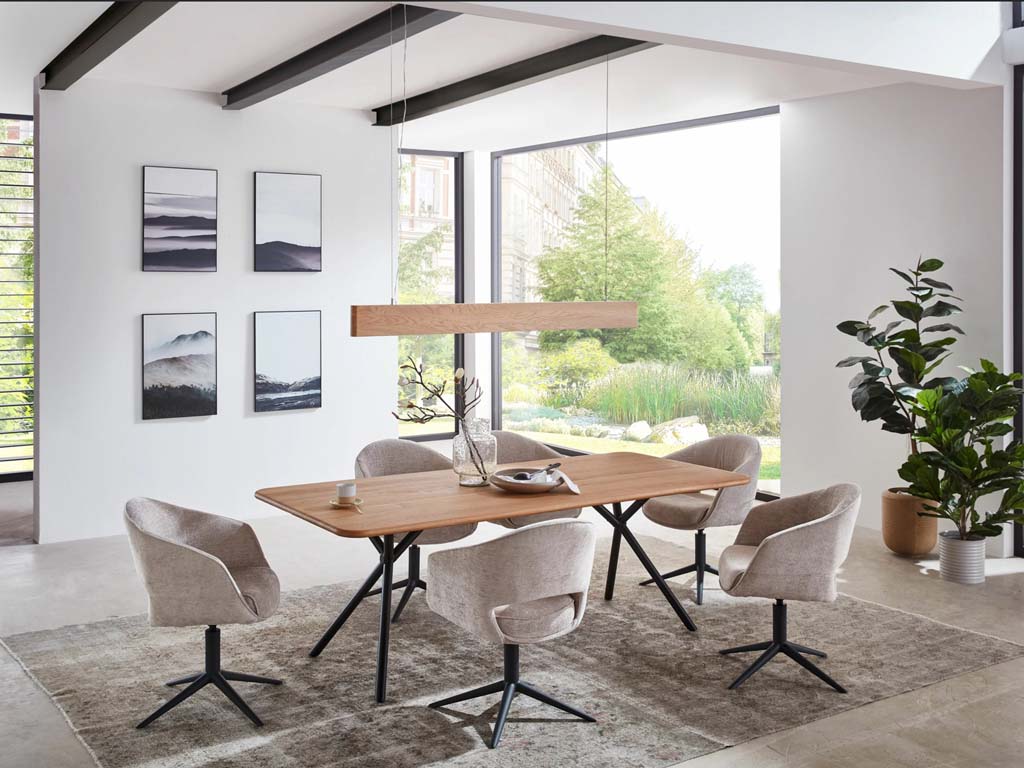 sechs beige stühle auf schwarzem gestell und braunem tisch mit lampe in einem hellen zimmer mit großen fenstern und grau gemustertem teppich mit bildern an der wand und pflanzen