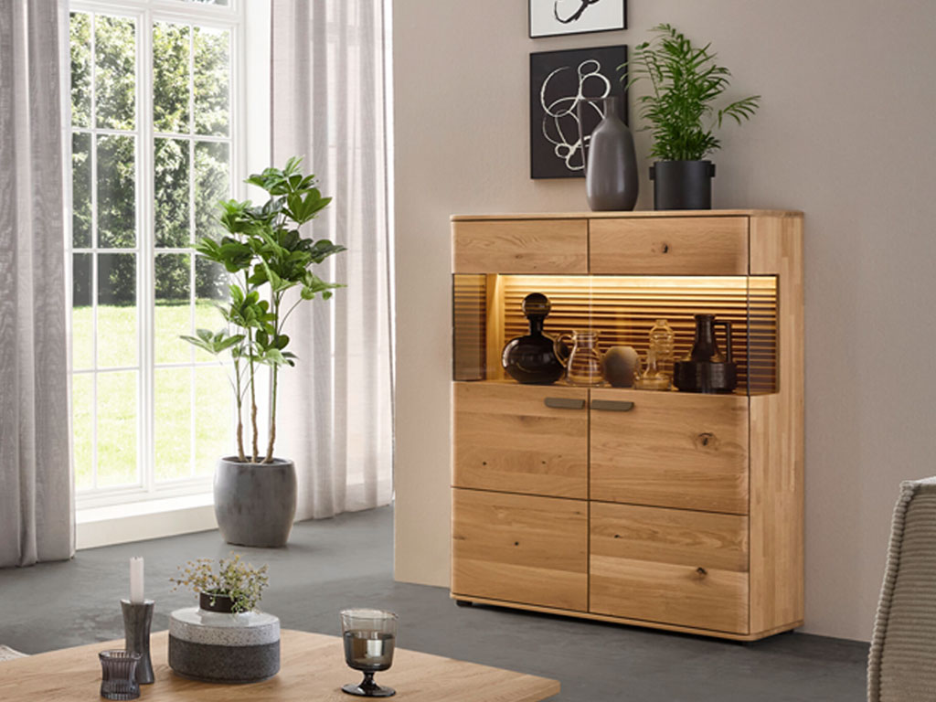 modernes Highboard aus Holz mit einem großen Vitrinenausschnitt und indirekter Beleuchtung stilvoll dekoriert in einem modernen Zimmer