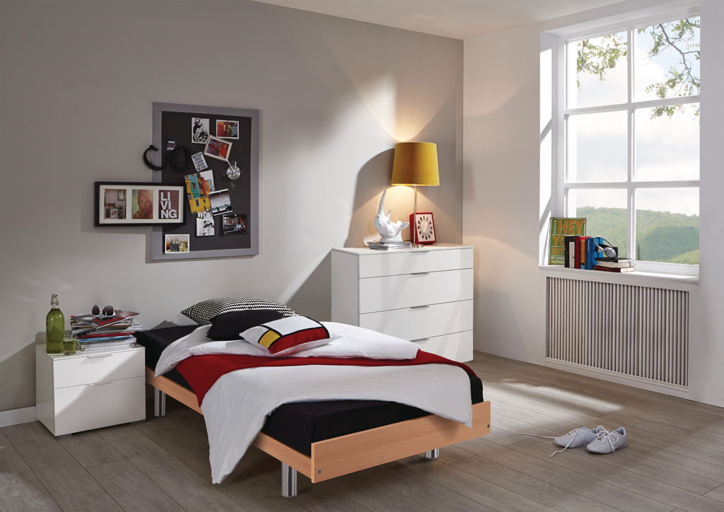 Einzelbett in Buche-Nachbildung mit glänzenden Chromfüßen, schwarz-weißer Bettwäsche und roter Decke in einem modern eingerichteten Jugendzimmer