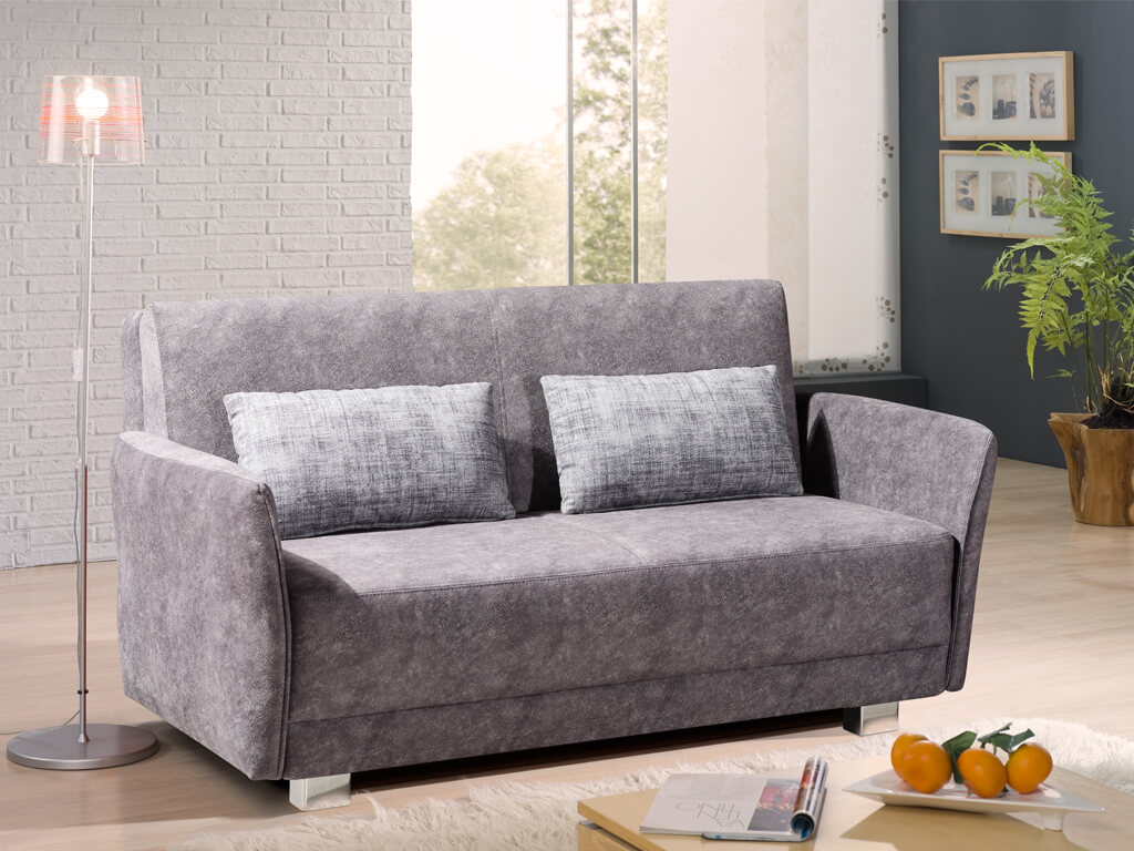 Restyl Vally - Schlafsofa (Faltsofa) | mit 2 Armteilen und Kissen | grau | 145 x 200 cm Ein modernes, graues Sofa mit zwei Kissen in einem stilvoll eingerichteten Wohnzimmer mit Stehlampe, Bildern an der Wand und einem Beistelltisch mit Dekoration.