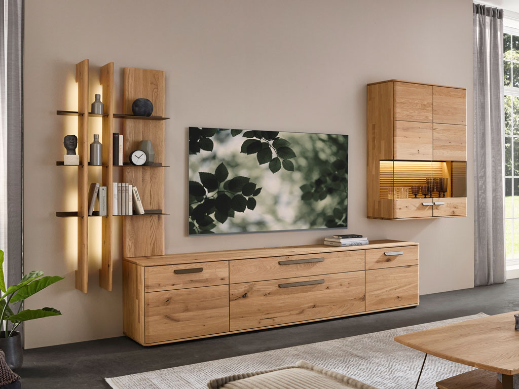 moderne Wohnwand aus Eiche mit einem großen Lowboard, beleuchtetem Regal und beleuchteter Hängevitrine stilvoll dekoriert in einem modernem Zimmer