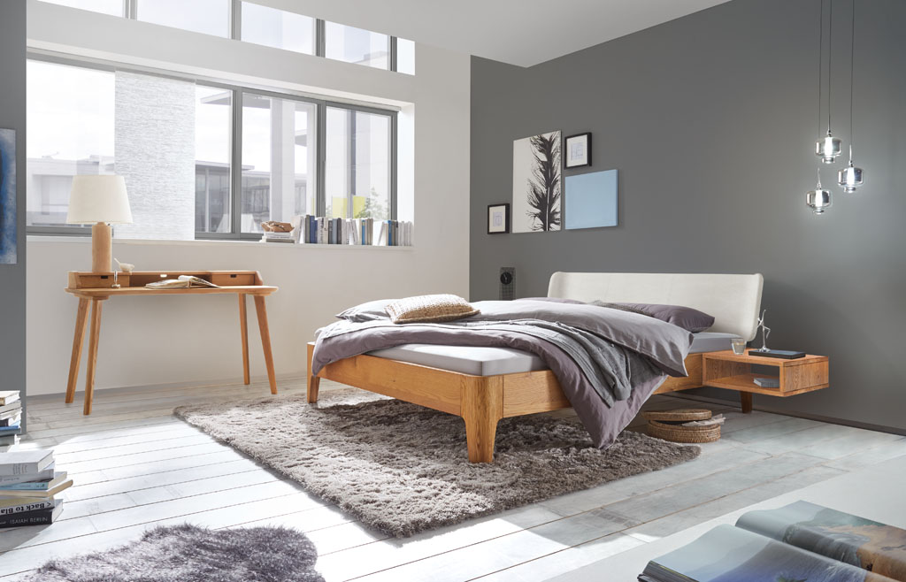 modernes Bett in braun mit geschwungenem Polsterkopfteil in weiß stilvoll dekoriert in einem modernen Zimmer