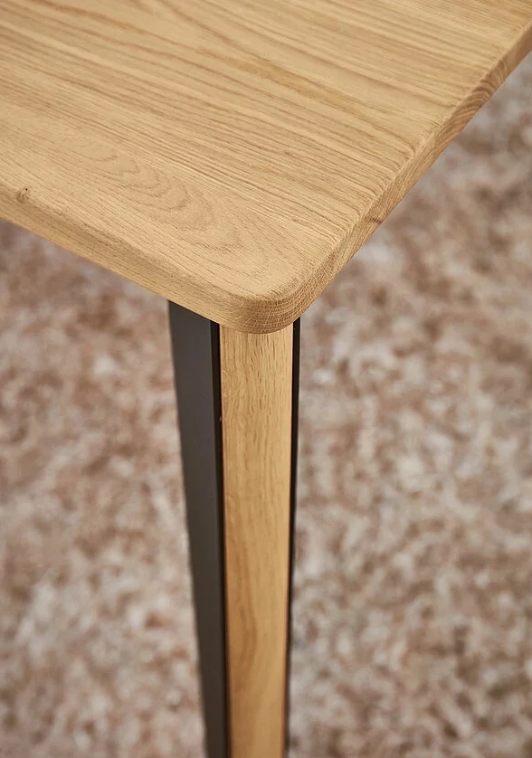 Nahaufnahme eines eleganten Holztisches mit abgerundeter Kante und robustem Design.