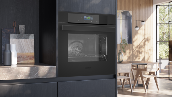Eingebauter Siemens Backofen mit geschlossener schwarzer Glasfront und TFT-Touchdisplay in einer dunklen Küchenzeile.