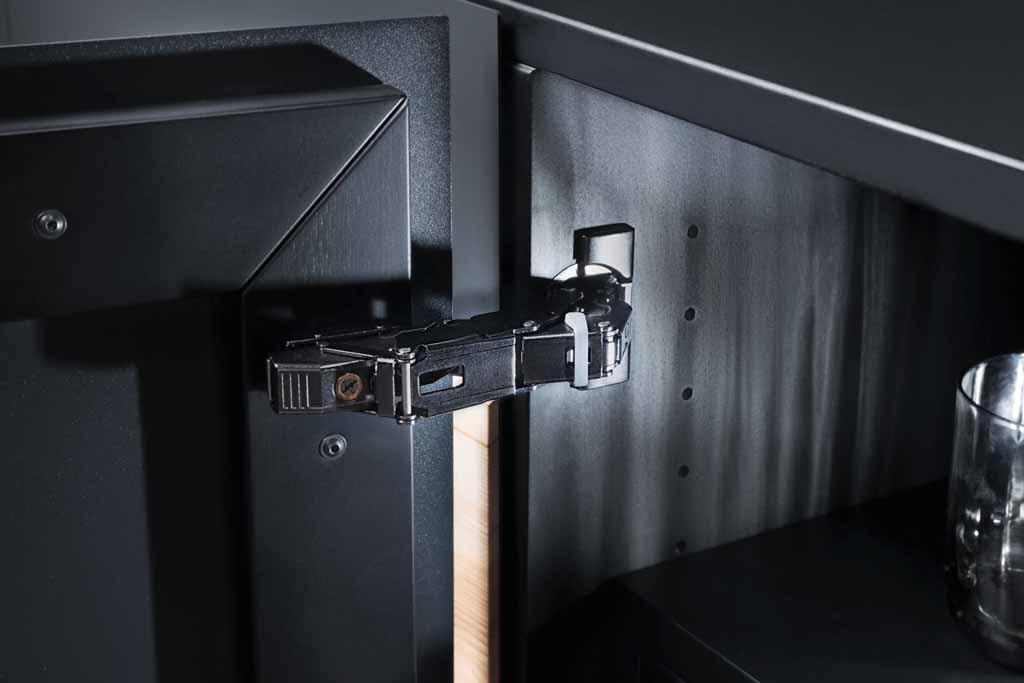 Nahaufnahme eines schwarzen Metallscharniers an einem Küchenschrank