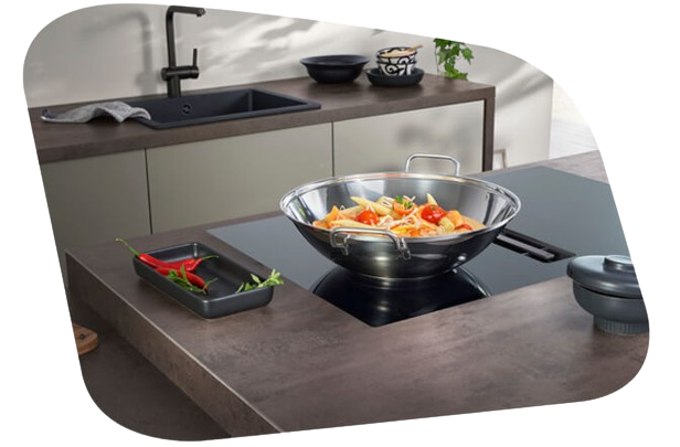 Silbernes Kochgeschirr mit hohem Rand / Wockstil, gefüllt mit Pasta auf einem Siemens studioLine Induktionskochfeld.