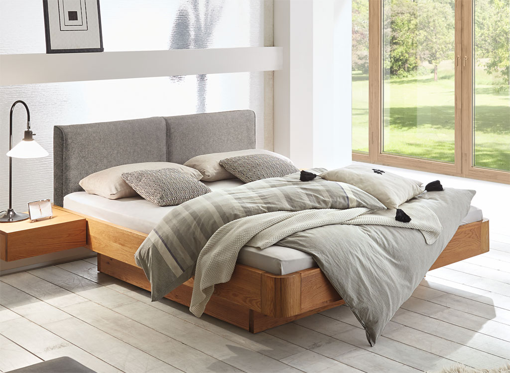 braunes modernes Bett mit braunem Bettkasten und Hängenachtschrank mit grauem Polsterkopfteil und passender brauner Kommode mit drei Schubladen stilvoll dekoriert in einem modernen Zimmer