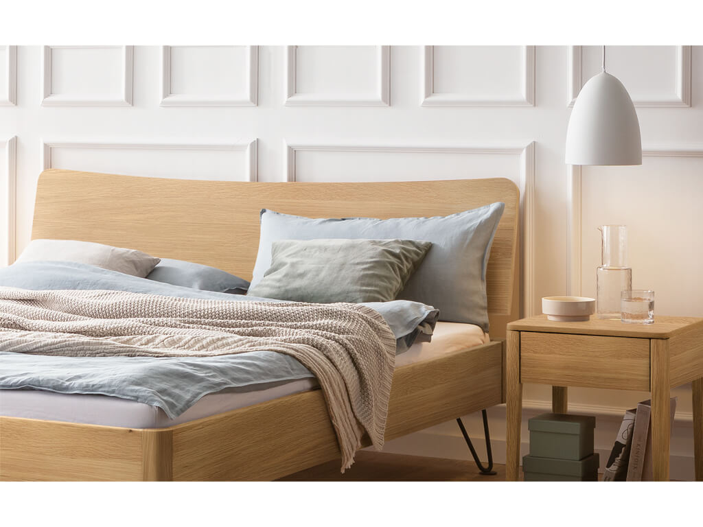 Nahaufnahme des Kopfteils eines Hasena Bett Locarno aus heller Eiche (Eiche bright), mit Bettwäsche und einem passenden Nachttisch.