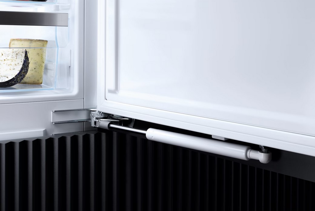 Nahaufnahme des Scharniers und der SoftClose-Technik (Türdämpfung) am unteren Ende des Miele Kühl-Gefrierschrankes, die für ein sanftes Schließen der Tür sorgt.