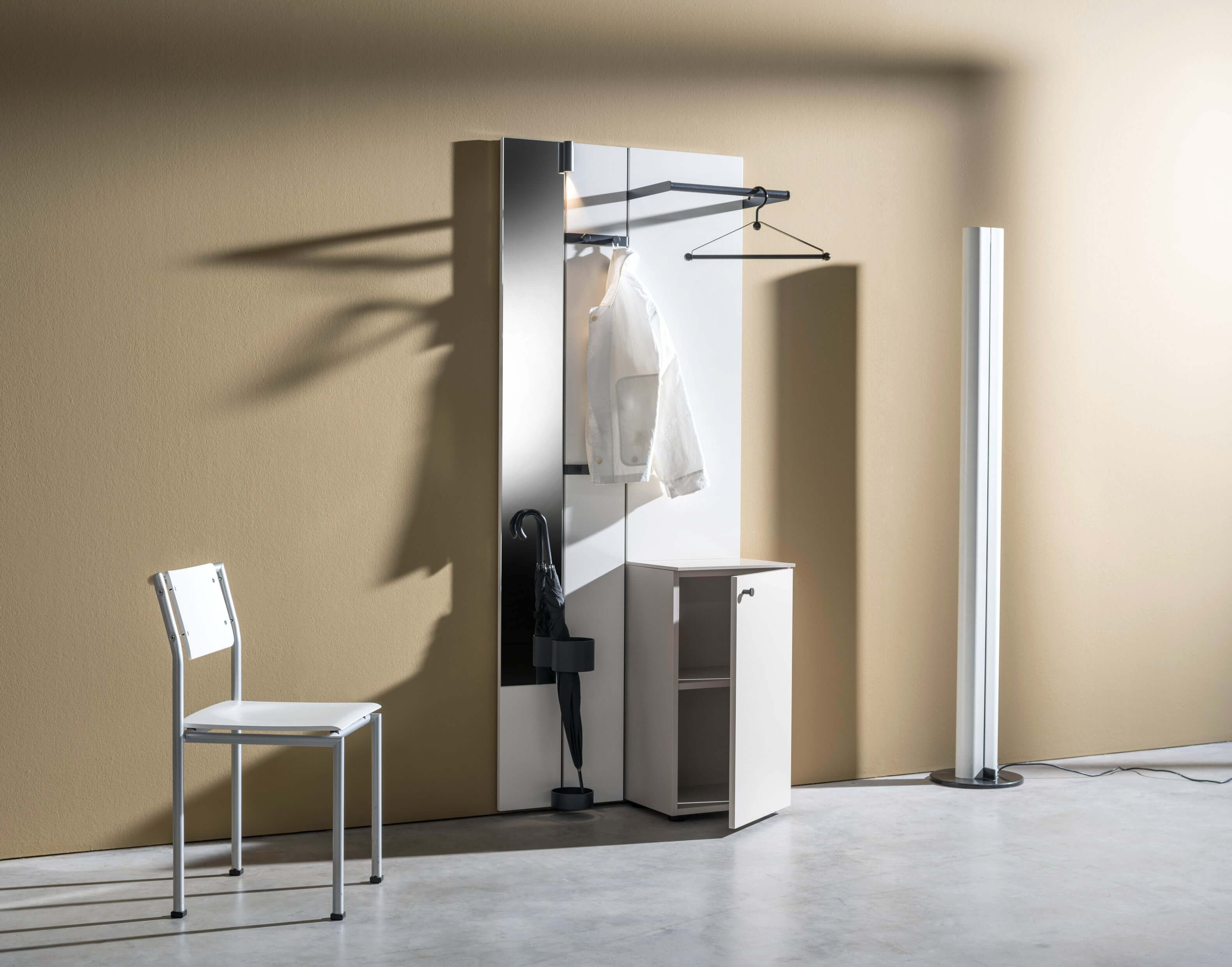 Flurspiegel mit Garderobenleiste, weißem Schrank und Stuhl in einem modern gestalteten Raum