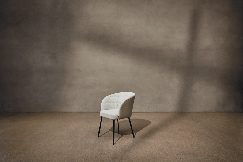 Eleganter Stuhl mit heller Polsterung vor einer schlichten, grauen Wand