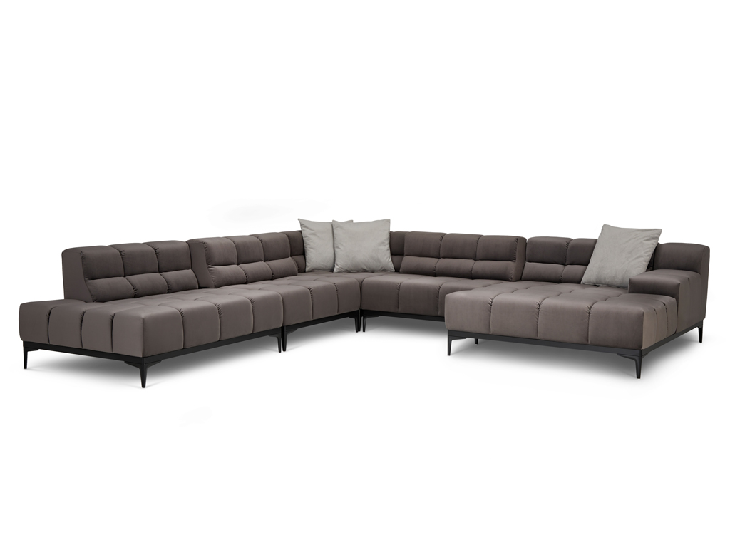 Ein großes U-förmiges Ecksofa in dunklem Taupe mit gesteppten Sitz- und Rückenkissen und schlanken schwarzen Metallfüßen. Zwei hellgraue Zierkissen liegen auf der Rückenlehne. Der Hintergrund ist weiß.